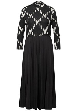 Black long-sleeve dress with high neck, patterned white and black knit top, and solid black pleated skirt extending to mid-calf.