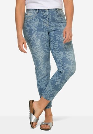 Jeans di jeans blu chiaro con motivo floreale, slim fit, cinque tasche e design a vita media. Indossati con sandali slide argento.