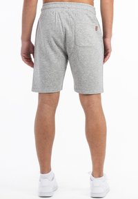 Šedé šortky z bavlněné směsi s elastickým pasem, jednou zadní kapsou a malou nášivkou loga, spárované s bílými teniskami.