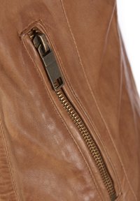 Materiale in pelle marrone con una cerniera metallica prominente a denti esposti, posizionato su una superficie liscia e texturizzata.