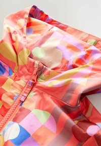 Bunte Jacke mit verschiedenen Farben, darunter Rot, Pink und Grün. Leichtes Material, frontale Reißverschlussöffnung und Kapuzenform.