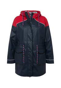 Veste imperméable marine avec des accents rouges, capuche, fermetures à glissière et à pression, deux poches frontales et cordons multicolores. Présente un passepoil blanc.