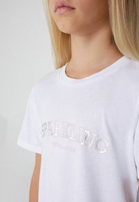 Weißes Baumwoll-T-Shirt mit den Aufdrucken "SPARKLING" und "CHEERLEADER" in schimmernden Buchstaben, rundem Ausschnitt und kurzen Ärmeln.