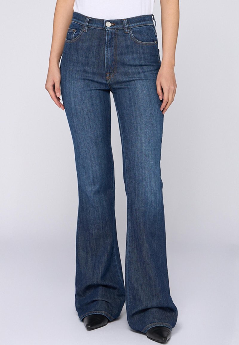 Jeans de mezclilla acampanados en azul oscuro con una textura suave. Presenta cinco bolsillos, botón de metal y costuras contrastantes a lo largo de las costuras.