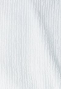 Biała tkanina o teksturowanym, prążkowanym wzorze. Powierzchnia wydaje się lekko prześwitująca, z subtelnymi różnicami w głębi i odbiciu światła.