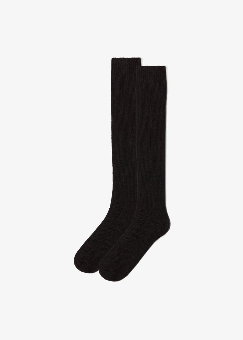 Paire de longues chaussettes noires à côtes, montant jusqu'au genou, présentées à plat sur un fond blanc.