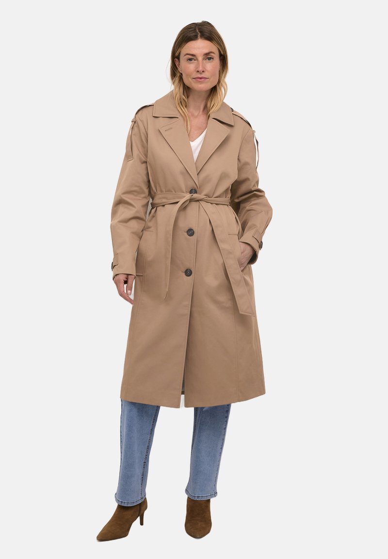 Béžový trench coat s páskem, velkými knoflíky a ramenními epaulety; vyrobený z hladké tkaniny; má dlouhé rukávy a délku po kolena.