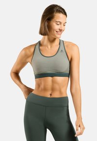 Soutien-gorge de sport gris clair avec des accents vert foncé, réalisé en tissu lisse et extensible, doté d'un design à dos nageur et d'un détail de logo sur la poitrine.