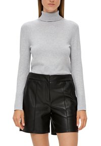 Hellgrauer Rollkragenpullover aus weichem Material mit langen Ärmeln, kombiniert mit hochgeschnittenen schwarzen Ledershorts, die gestickte Details aufweisen.