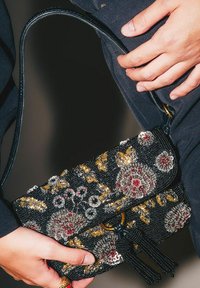 Borsa nera perline con motivi floreali in oro, argento e rosso, dotata di nappina, tracolla e chiusura a scatto.