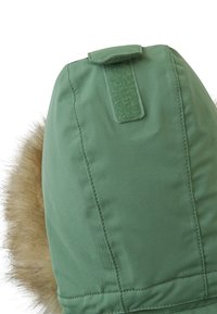 Parka verde con cappuccio foderato in pelliccia sintetica, dotato di un flap in Velcro per la regolazione e un'esterno in tessuto liscio e texture.