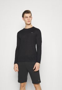 Black long-sleeve shirt with a crew neck and CK logo on the left chest, paired with black shorts, showcasing a smooth texture.