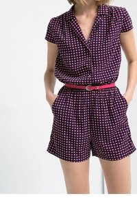 Mono corto de color púrpura oscuro con mangas cortas, pequeño patrón de corazones rosas, cintura ceñida con cinturón y bolsillos laterales. Tejido suave con un ajuste relajado.