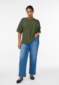 Olivově zelená texturovaná halenka s krátkými rukávy, kombinovaná s vysokým pasem, světle modrými džínami s rovnými nohavicemi a námořnicky modrými balerínami. Jednoduchý design.