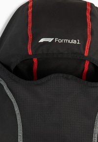 Zaino in tessuto nero con cuciture rosse e logo della Formula 1. Superficie testurizzata con forma strutturata e fodera interna liscia.
