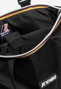 Intérieur d'un sac en tissu noir avec fermeture éclair, doté d'un bord rayé multicolore et d'un patch logo K-WAY visible.