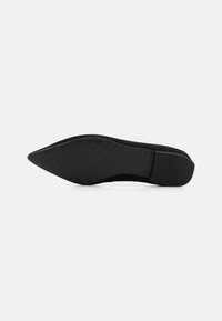 Sapato preto de camurça com bico fino, apresentando uma sola de borracha texturizada e um salto baixo. O design é elegante, com um acabamento suave.