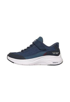 Baskets de sport bleu marine avec une texture matelassée, une sangle Velcro et une semelle en mousse blanche. Présente des accents sombres contrastés et le logo "Skechers Slip-Ins".