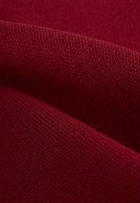 Tessuto a maglia bordeaux con una texture liscia e un fine motivo a coste, che mostra una ricca profondità di colore e sottili variazioni nella trama.