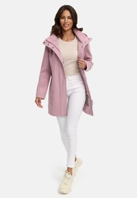 Light pink coat with a hood, button details, and pockets, worn over a beige top and white jeans, paired with cream sneakers.