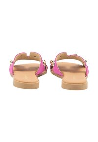 Sandalias planas fucsias con parte posterior abierta, con acentos dorados y una suela beige suave. Diseño minimalista con una textura suave.