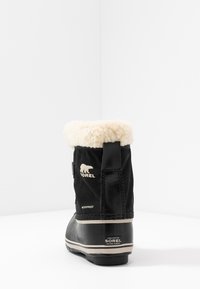 Svart vanntett støvel med en kremfarget faux-fur krage, gummisåle og Sorel-merke. Har en teksturert stoffskafte og solid hæl.