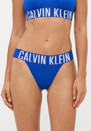 Blauwe Calvin Klein bralette en thong set, gemaakt van gladde stof. De band heeft gedurfde witte letters. Minimalistisch ontwerp met een rekbare pasvorm.