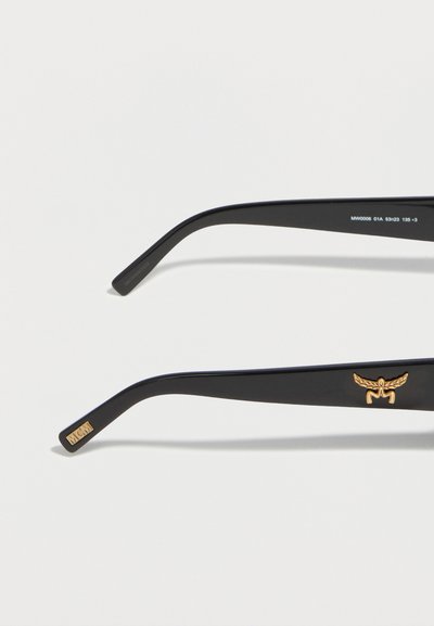 Black eyeglass arms with gold MCM logo and winged emblem, shown against a white background.