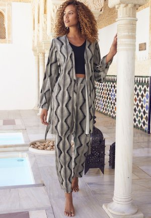 Lightweight black and white patterned outfit with a loose-fitting jacket and matching pants, set against a tiled, marble backdrop.