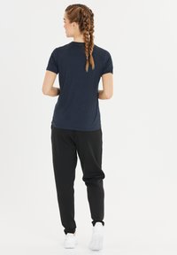 Mörkblå t-shirt med korta ärmar i kombination med svarta joggers. Mjuk bomullsblandning; joggers har elastiska mudd ärmar och vita sneakers.