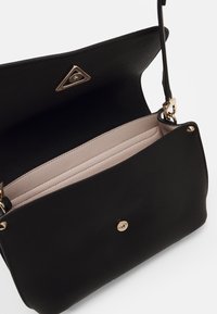 Black leather crossbody bag with a textured surface. Inside features a light pink lining and two compartments. Gold hardware accents.