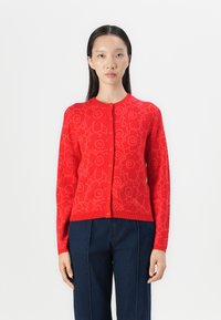 Red knitted cardigan with floral pattern, round neckline, and button closure. Features long sleeves and ribbed cuffs and hem.