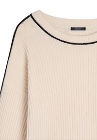 Suéter de punto acanalado color crema con un escote redondeado y un borde negro en el borde y los hombros. Textura suave y mangas largas.