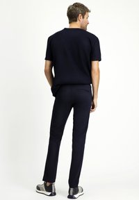 Camisa de manga corta azul marino combinada con pantalones ajustados azul marino y zapatos casuales. Tela suave con un diseño sencillo, sin patrones o detalles visibles.