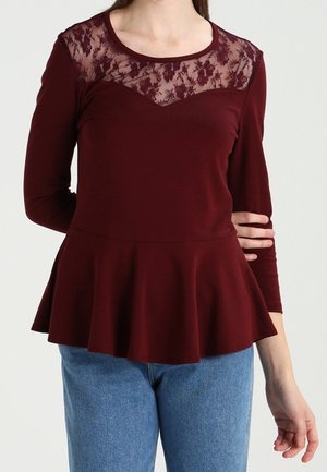 Burgunderfarbenes Langarmshirt mit Spitzen- und Blumenmuster-Einsatz sowie einem ausgestellten Peplumsaum. Hergestellt aus weichem Material mit einem runden Ausschnitt.