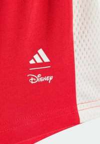 Camiseta deportiva roja con un panel de malla blanco, adornada con los logotipos blancos de Adidas y Disney. Tejido suave con costuras reforzadas.