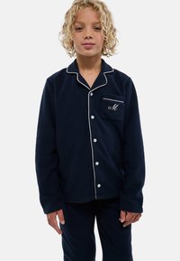 Ensemble de pyjama bleu marine en tissu doux avec passepoil blanc. Le haut à manches longues comporte une poche poitrine et une initiale brodée "M". Boutonné sur le devant.