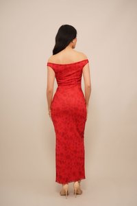Rochie roșie, cu umărul gol, cu un model floral, cu o siluetă ajustată și o suprapoză transparentă. Asociată cu pantofi cu toc în nuanțe nude.