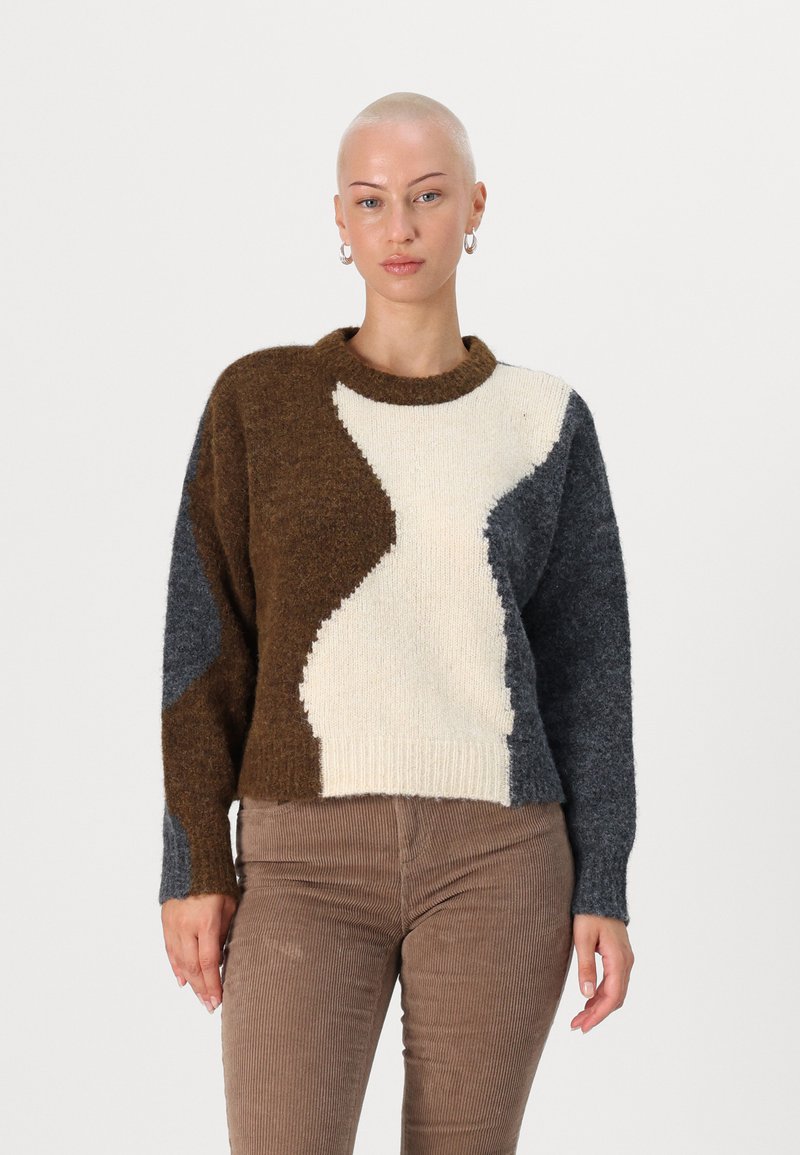 Pull en tricot avec un design en blocs de couleurs crème, marron et gris foncé, doté d'un col rond et d'un ourlet côtelé. Texture douce avec une coupe décontractée.