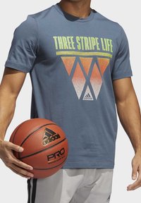 Šedé bavlněné tričko s grafikou "Three Stripe Life" v žluté a oranžové gradientní barvě; doplněné o hnědý basketbal.