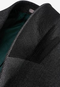 Collar de abrigo de patrón negro y gris con un suave forro interior verde oscuro. Presenta un acento de fieltro negro texturizado en el collar.