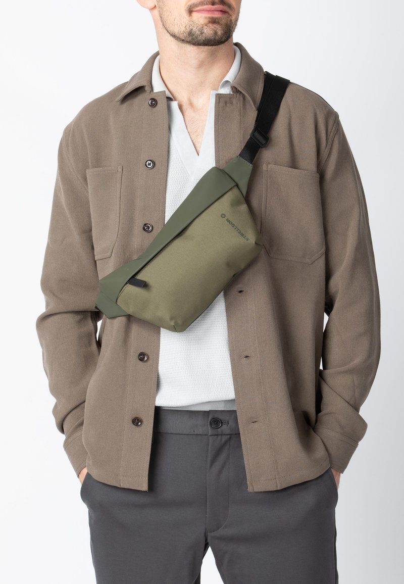 Borsa a tracolla in verde oliva, realizzata in materiale resistente, con un design rettangolare elegante e una tracolla regolabile per un comfort ottimale.