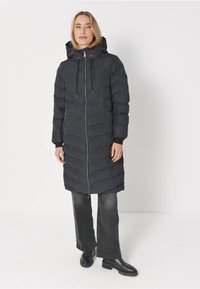 Svart pufferjacka med huva, med dragkedja fram, horisontellt quiltad mönster och sidofickor. Långa ärmar och knälång design.