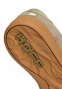 Suola di scarpa HOFF beige con grip in gomma leggera marrone chiaro testurizzata e nome del marchio in rilievo vicino al tallone.