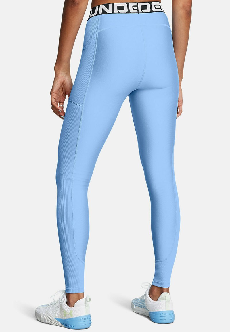 Leggings bleu clair avec une texture côtelée, dotés d'une taille élastique noire portant l'inscription "UNDER" et d'une poche latérale pour le rangement.