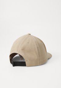 Beige színű baseball sapka, pamutból készült, ívelt csúccsal, hat paneles kialakítással és hátul állítható fekete pánttal.