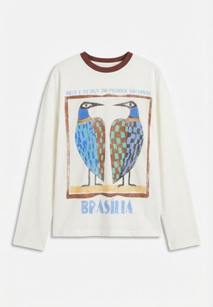Langermet hvit skjorte med brun krage, med to stiliserte fargerike fugler og teksten "Arte e Design do Parque Nacional Brasília".