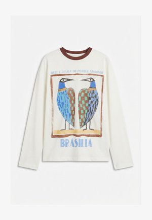 Langermet hvit skjorte med brun krage, med to stiliserte fargerike fugler og teksten "Arte e Design do Parque Nacional Brasília".