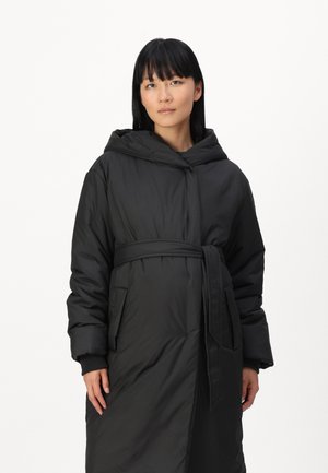 Must must coat, mille vöödiga, kapuutsiga ja küljetaskutega. Omab sujuvat, kerget tekstuuri ja pikka, ülemõõdulist lõike.