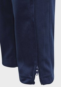 Pantalones deportivos azul marino de tejido texturizado, con un zipper lateral en el bajo y detalles de costura para mayor durabilidad.